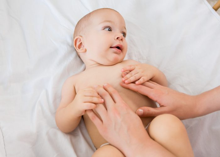 Hands of a mother playing with baby boy on a cradle at home